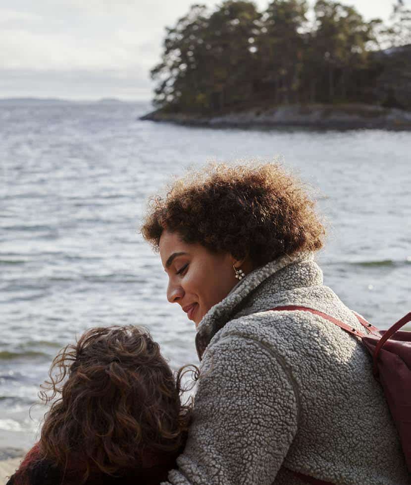 Two young people sitting together by the sea on an overcast day.